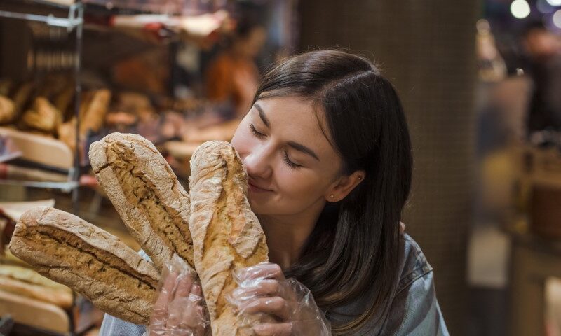 Only the best and fresh bakery. Young woman in supermarket with fresh bread . Health food. Healthy food, organic products.